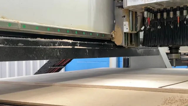 Close-up of a CNC spindle and dust brush above sheet material