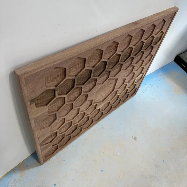 Angled close-up of a CNC-routed honeycomb pattern in wood