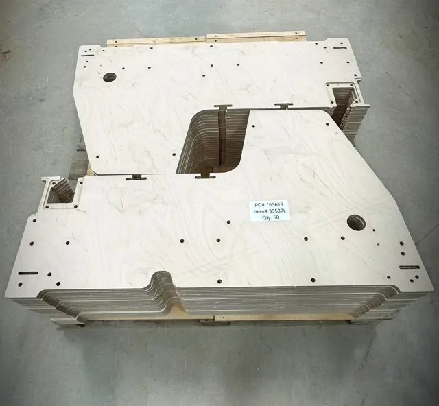 Stacked CNC-cut plywood components with drilled holes and cutouts