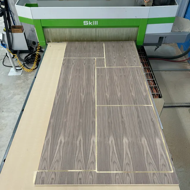Wood-grain sheet with routed outlines on a CNC table